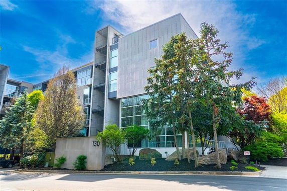 Front view of a modern multi-story building with large windows and surrounding trees.