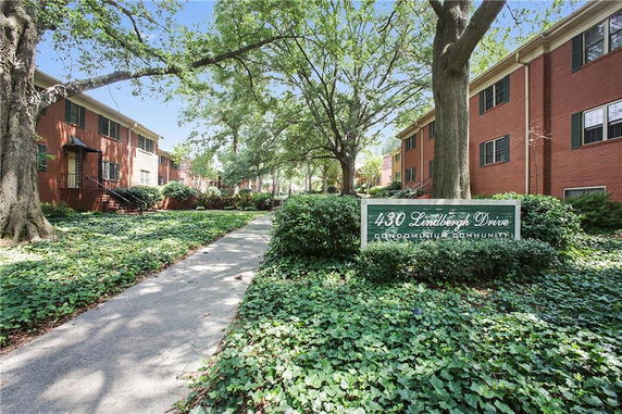 Front view of a condominium building with red brick exterior and green shutters.