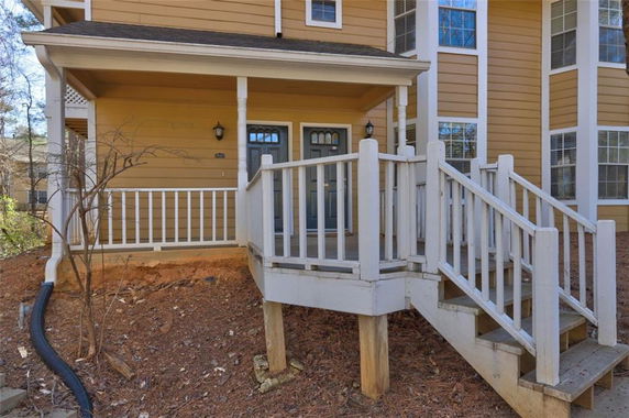 Front view of a two-story house with wooden steps and porch.