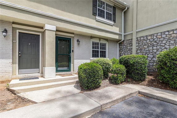 Front view of a two-story building entrance with shrubs and stone accents.