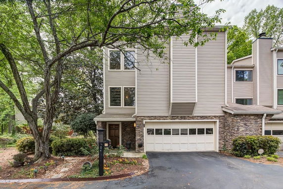 Front view of a multi-story house with a garage and stone facade.