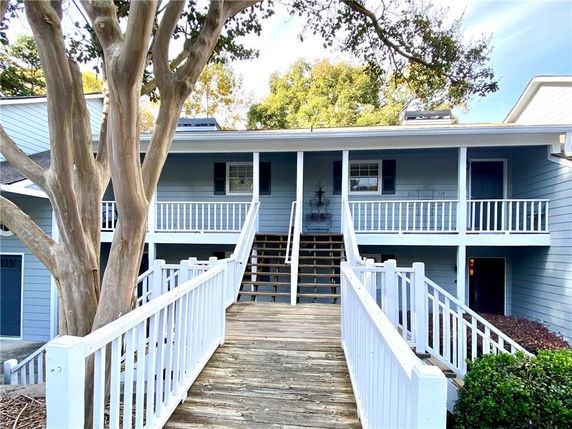 Front view of a residential building with a wooden staircase and white railings.