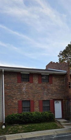 Front view of a two-story brick house with red shutters.