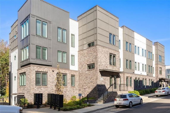 Front view of a modern three-story residential building with brick and panel facade.