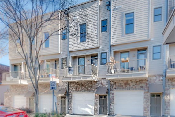 Front view of a multi-story townhouse with garages and balconies.