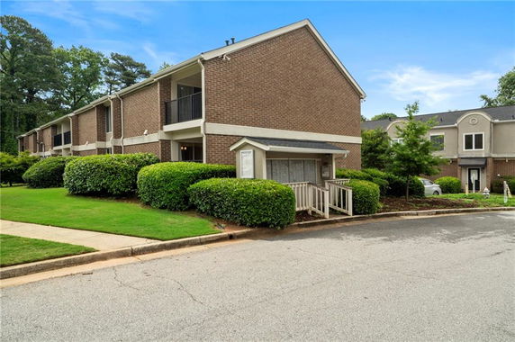 Front view of a two-story brick apartment building with greenery.