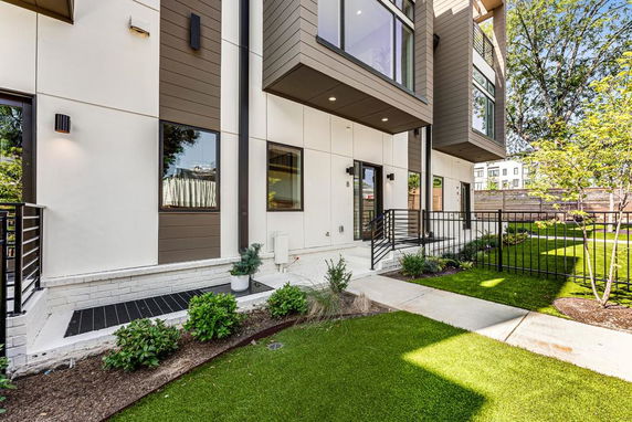 Front view of a modern multi-story building with large windows and landscaped garden area.