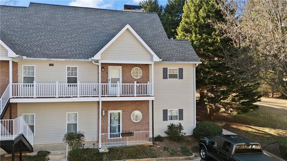 Front view of a two-story house with an external staircase and balcony.