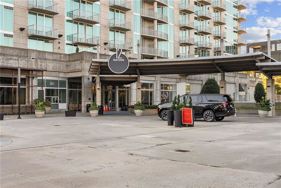 Front view of a multi-story building with glass balconies and a prominent entrance.