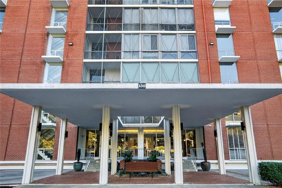 Front view of a multi-story building with a brick facade and glass balconies.