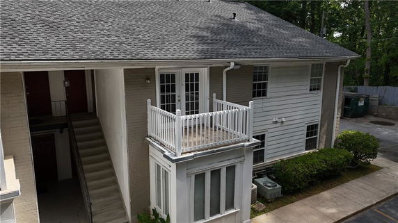 Exterior view of a two-story building with a small balcony and staircase entrance.