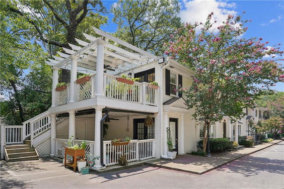 Front view of a two-story house with a white wooden exterior and a second-floor balcony.