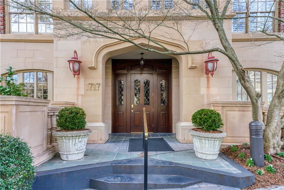 Front view of a building entrance with an arched doorway and potted plants.
