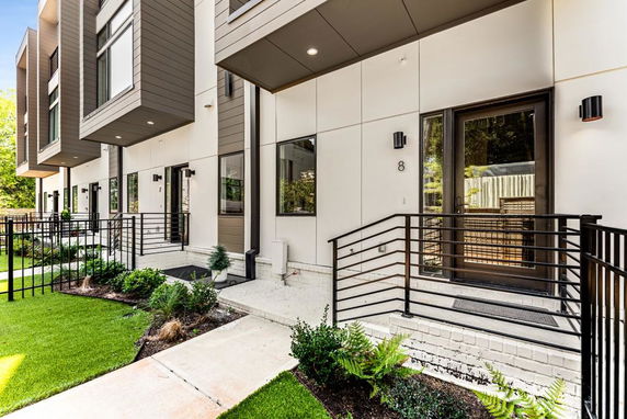 Front view of modern multi-story townhouses with glass doors and metal railings.