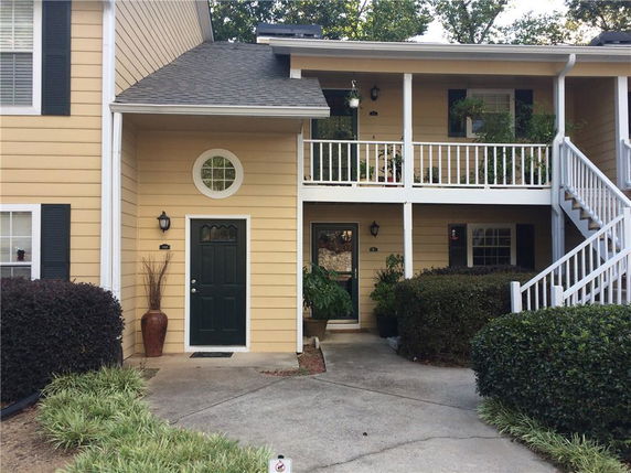 Front view of a house with an upper balcony and external stairs.