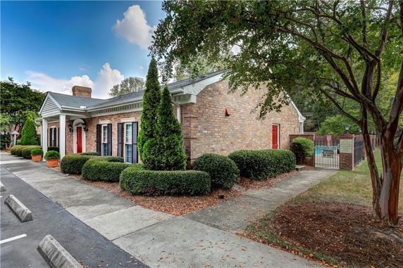Front view of a single-story brick building with red doors and white trim.