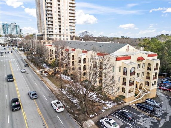 Front view of a multi-story building with balconies and a parking area in an urban setting.