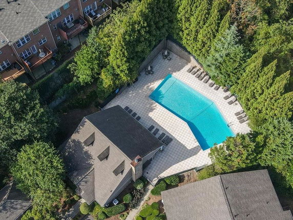 Aerial view of a residential swimming pool surrounded by trees and houses.