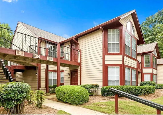 Front view of a two-story apartment building with wooden exterior and red accents.