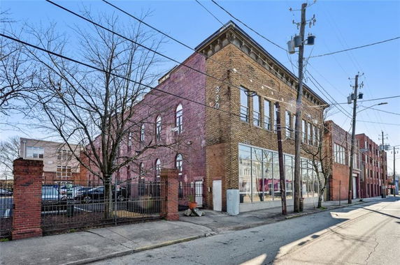 Front view of a brick building with large windows and multiple stories.