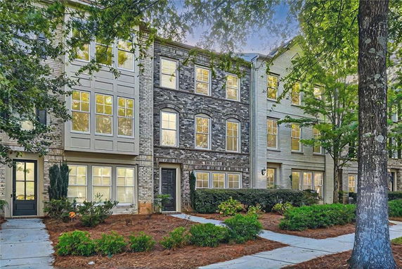 Front view of a multi-story townhome with brick facade and multiple windows.