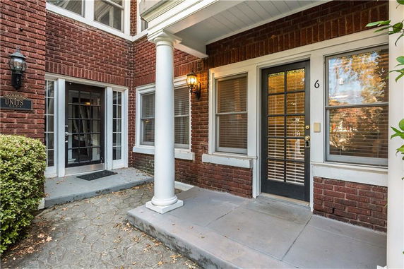 Front view of a brick building with white columns and glass-paneled doors.