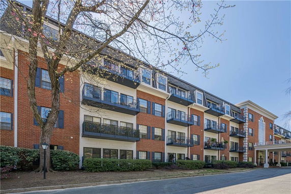 Front view of a multi-story brick apartment building with balconies.