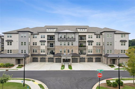 Front view of a multi-story apartment building with garages and balconies.