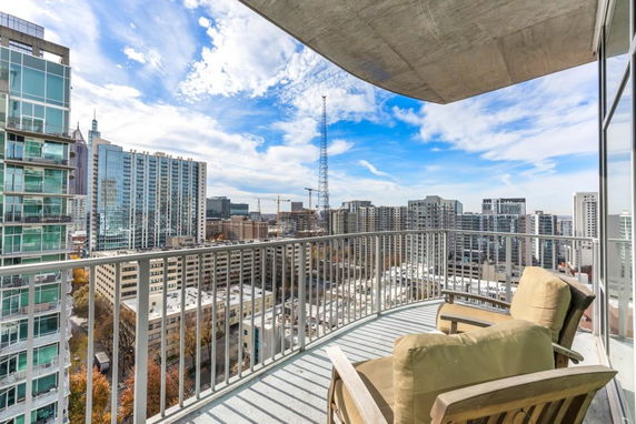 Panoramic view from a balcony overlooking a cityscape with high-rise buildings and a clear sky.