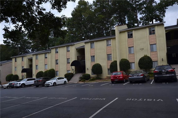 Front view of a three-story apartment building with parking area in front.