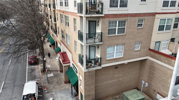 View of a multi-story building with balconies and street-level shopfronts.
