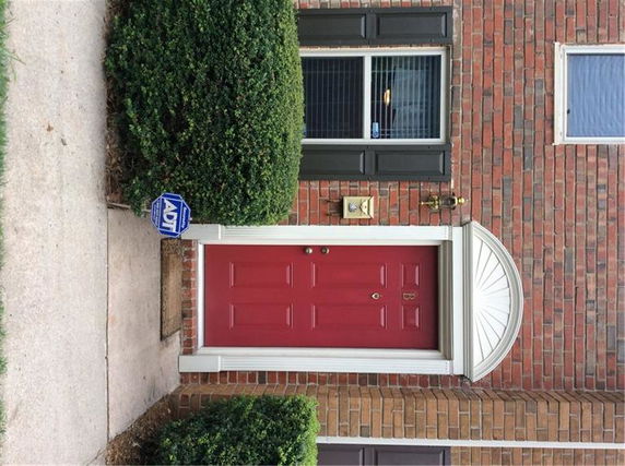Front view of a house entrance with a red door and brick exterior.