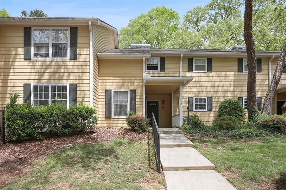 Front view of a two-story house with yellow siding and green shutters.
