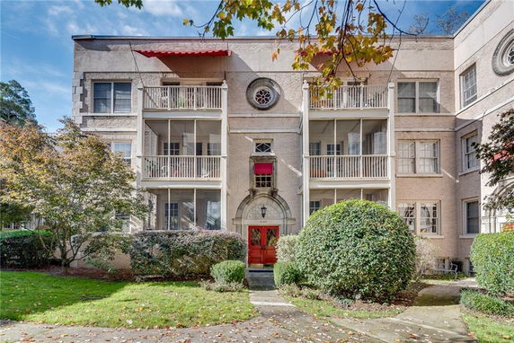 Front view of a multi-story apartment building with balconies and a red entry door.