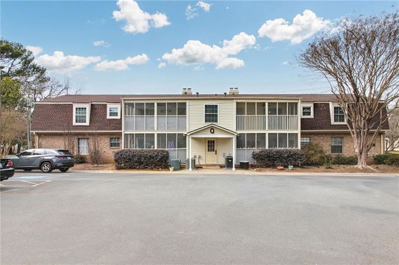 Front view of a two-story residential building with a central entrance and screened balconies.