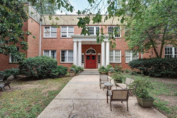 Front view of a two-story brick building with a central red door and white columns.