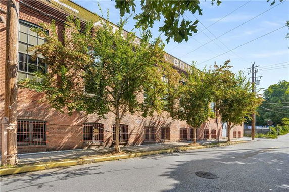 Front view of a brick building with large windows and trees lining the sidewalk.