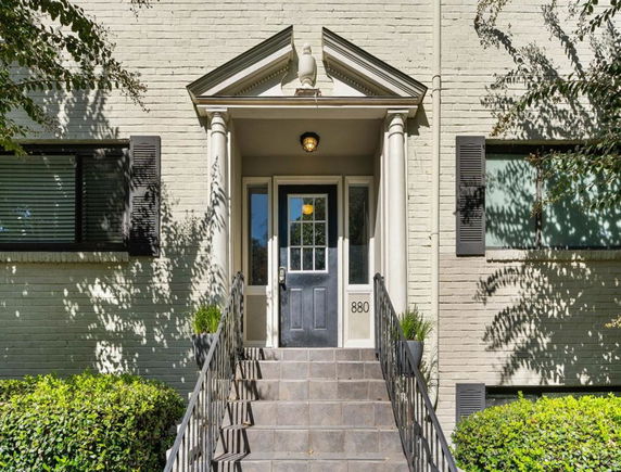 Front view of a building entrance with stairs and a decorative doorway.
