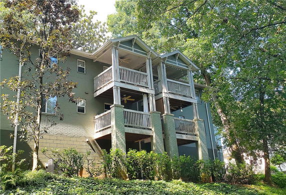 Front view of a multi-story house with balconies and green exterior.