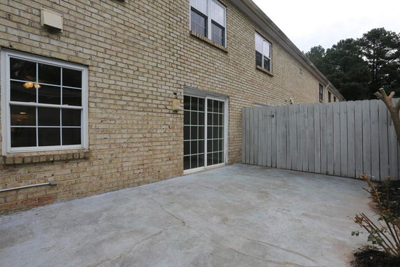 Exterior view of a brick house with sliding glass door and windows.