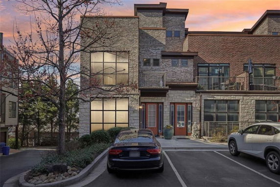 Front view of a multi-story building with a brick and stone facade and parking area.
