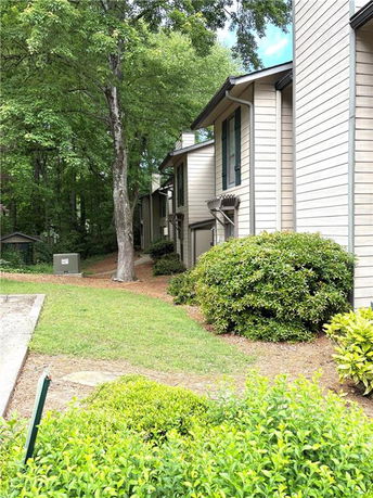 Side view of a building with multiple units and shrubbery.