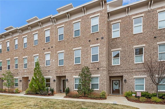 Front view of a multi-story brick townhouse with multiple windows.