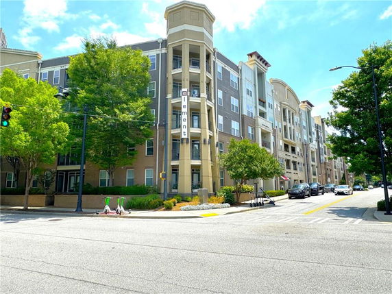 Front view of a multi-story apartment building on a street corner.