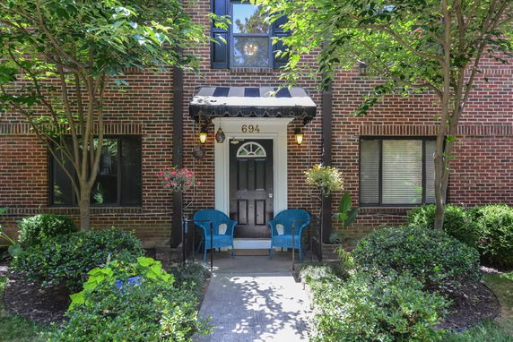Front view of a house with a door and two chairs under an awning.