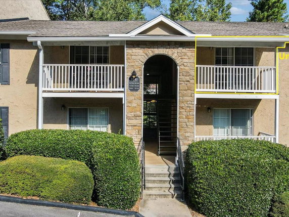 Front view of a two-story apartment building with balconies and an entrance arch.