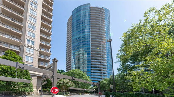 Front view of a tall, cylindrical glass skyscraper with adjacent building.