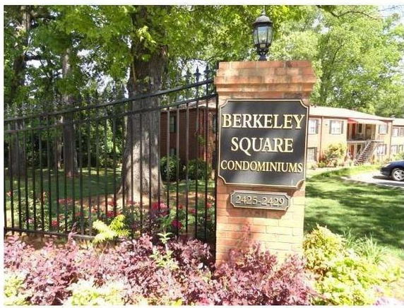 Front view of a condominium complex with entrance sign and building in the background.