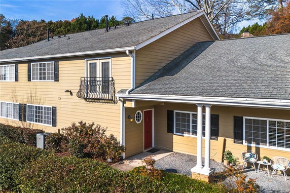 Front view of a two-story yellow house with a small balcony and a red door.