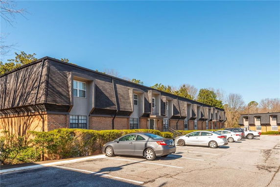 Front view of a two-story apartment building with brick facade and dormer windows.